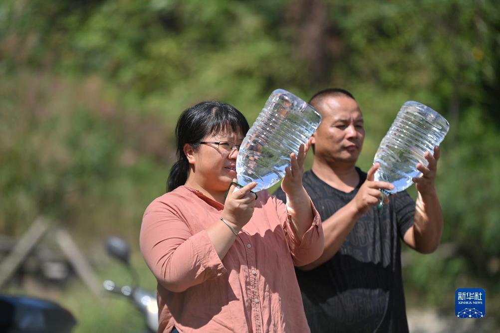 楊寧（左）在查看村民剛剛采集的水樣，為山泉水引水工程做準備（10月8日攝）。新華社記者 黃孝邦 攝